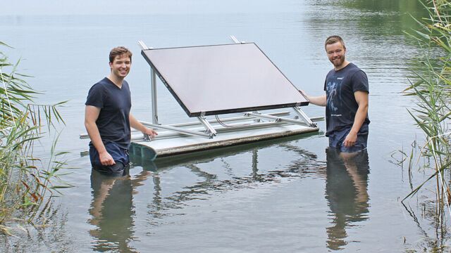 Zwei Männer stehen im See und in der Mitte schwimmt ein Solarmodul