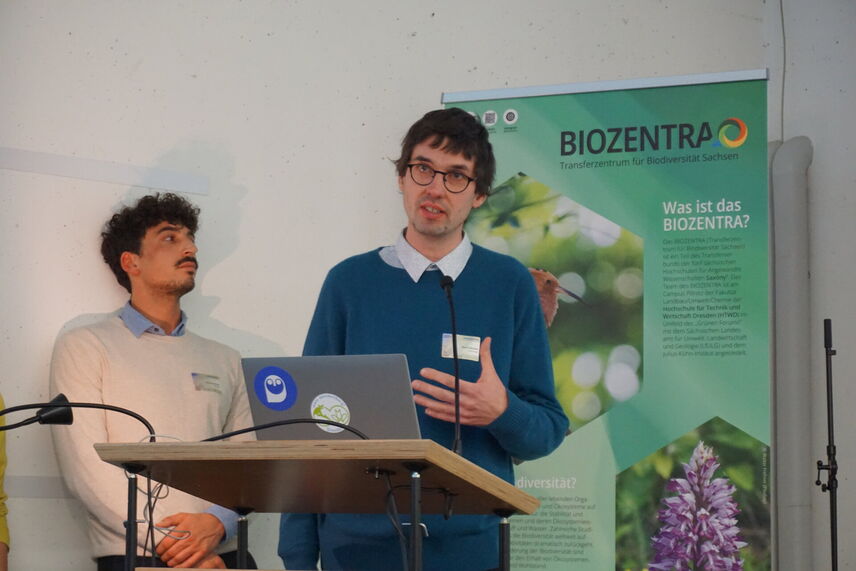 Ein Mann, der neben einem anderen Mann steht und einen Vortrag hält.