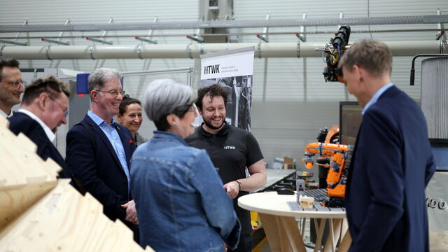 Mehrere Personen schauen auf ein Robotermodell in einer Halle