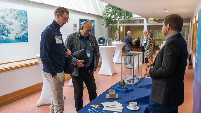 Drei Männer stehen am Stand und unterhalten sich.