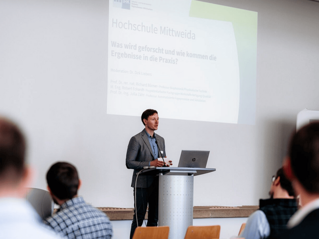 Dirk Liebers steht am Pult und moderiert.