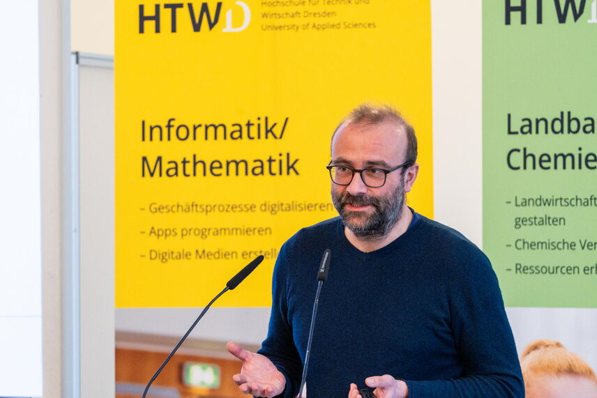 Ein sprechender Mann, der vor einer Wand mit bunten Postern steht .