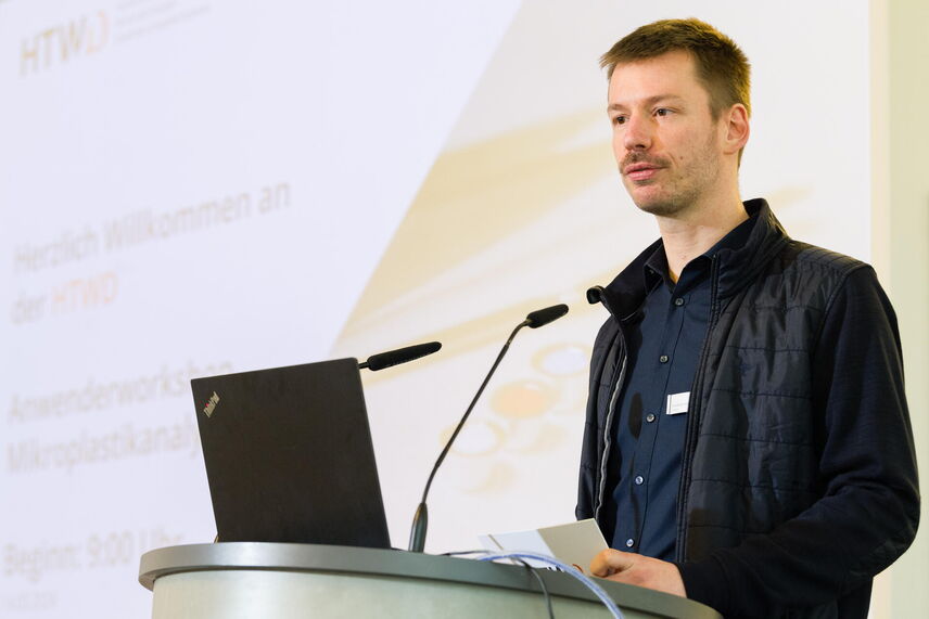 Lucas Kurzweg spricht am Podium, im Hintergrund ist die Präsentation zu sehen.