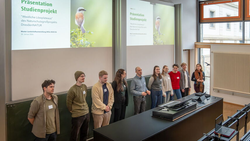 Studierende, die auf der Bühne eines Hörsaals stehen.