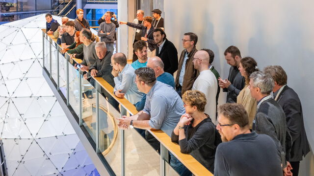 Eine Reihe von Personen steht auf einem Balkon und blickt hinab in die Gläserne Manufaktur.