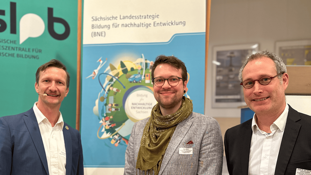 Drei Männer die vor einer bunten Fläche stehen