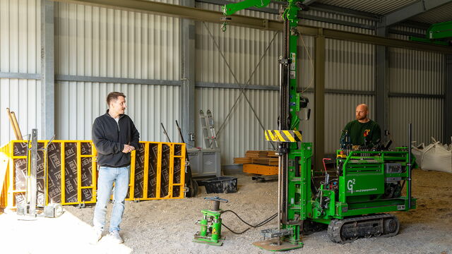 Links steht ein Mann im Geotechnikum, rechts sitzt ein weiterer auf einem großen grünen Rammsondiergerät