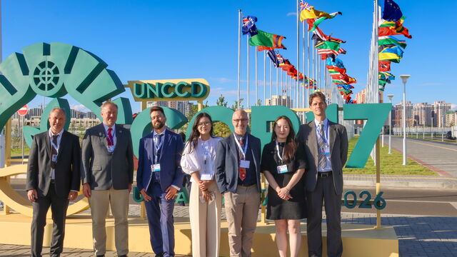 Menschen, die vor einem Schild "UNCCD COP17, Ulaanbaatar 2026" stehen.