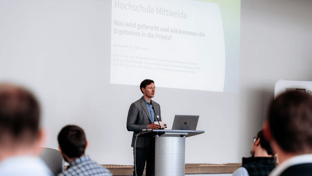 Dirk Liebers steht am Pult und moderiert.