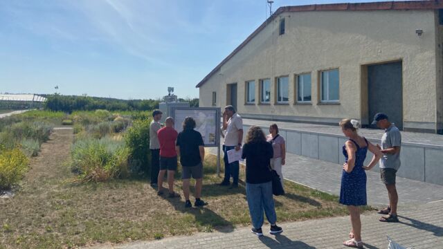 Menschengruppe vor einer Infotafel im Rahmen eines Exkursionsspaziergangs