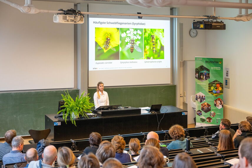 Eine Frau, die einen Vortrag vor einem Publikum hält.