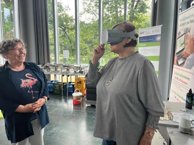 Zwei Seniorinnen, eine von ihnen probiert eine VR-Brille aus