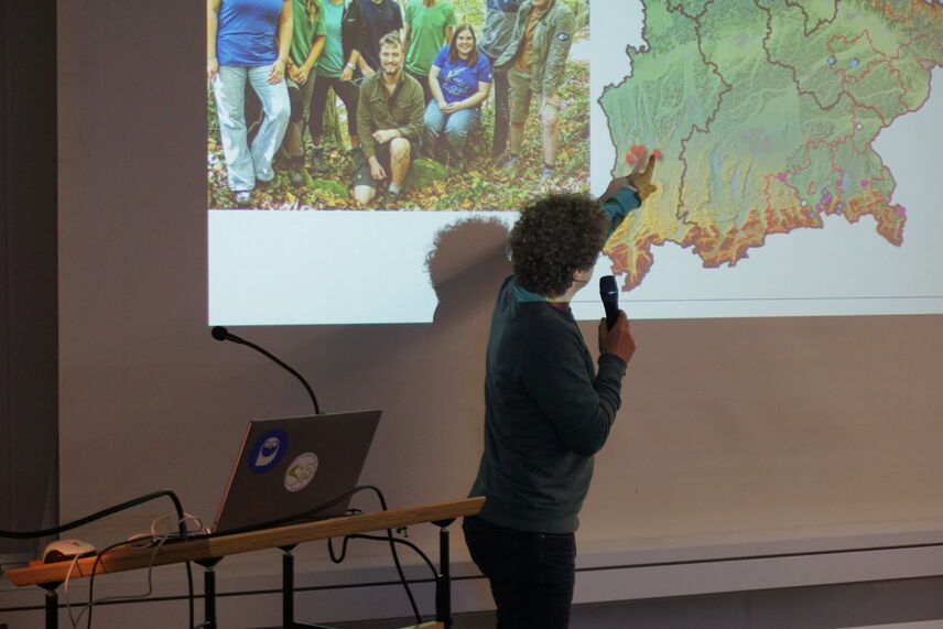 Ein Mann, der einen Vortrag hält und auf einen Punkt auf einer Karte zeigt.