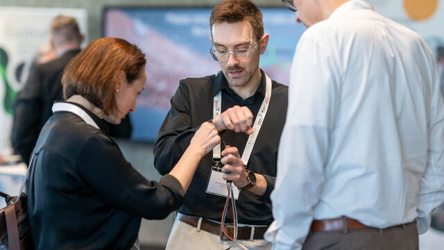 Drei Personen betrachten einen Sensor mit Kabel.