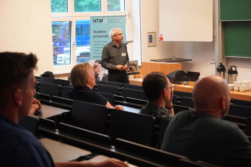 Blick auf Dr. Tom Weier vom HZDR, der in einem Hörsaal einen Vortrag hält, im Vordergrund interessierte Zuhörende