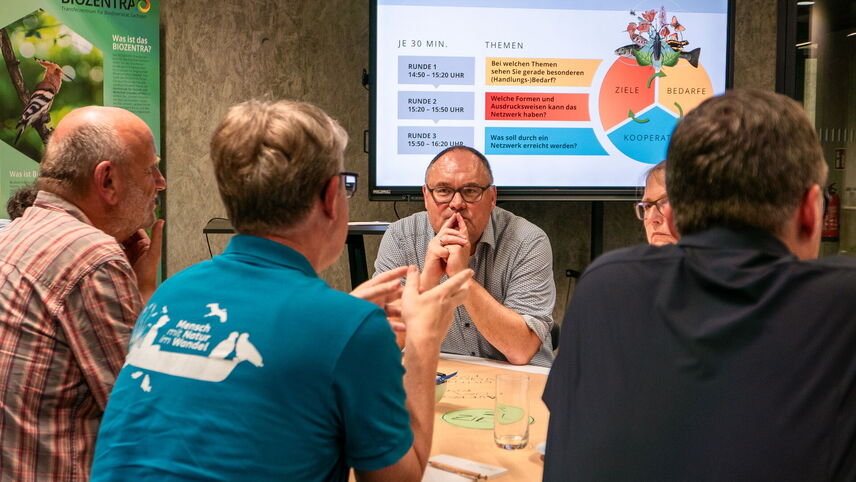 Menschen, die an einem Tisch sitzen und sich unterhalten.