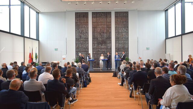 Blick von hinten durch den Bürgersaal auf die Teilnehmenden und das Podium.