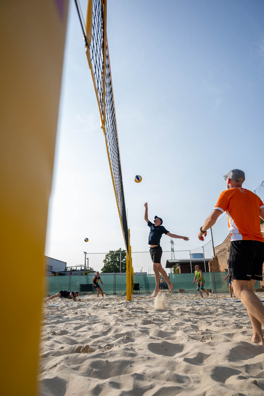 Eine Person springt an einem Volleyballnetz hoch, um den Ball zu schlagen.