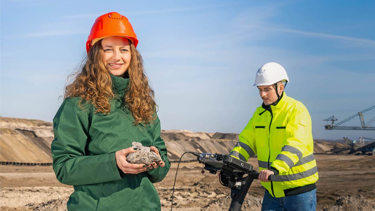 Zwei Personen auf einer Baustelle mit Schutzhelmen.