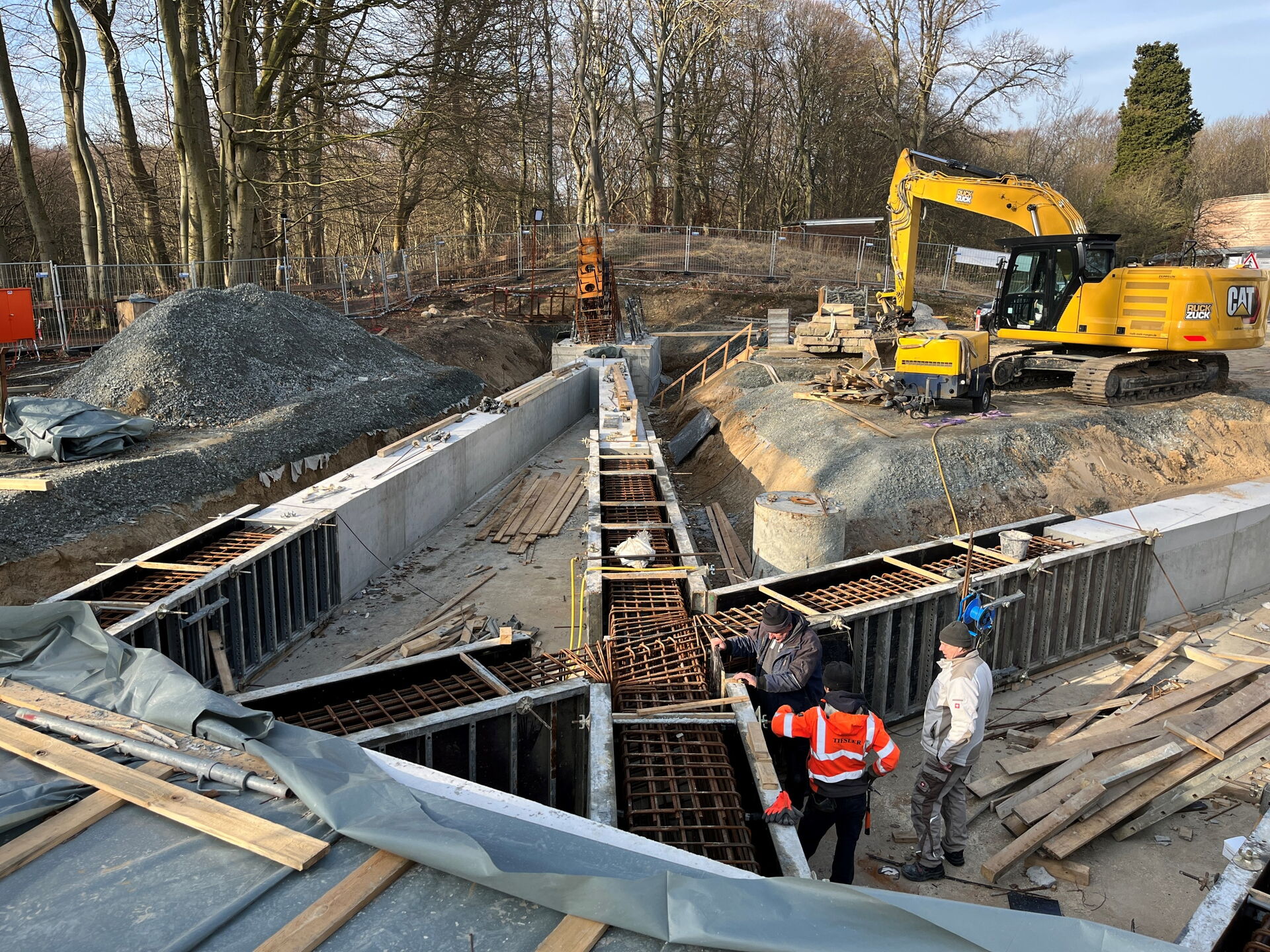 3 Personen und ein Bagger auf einer Baustelle