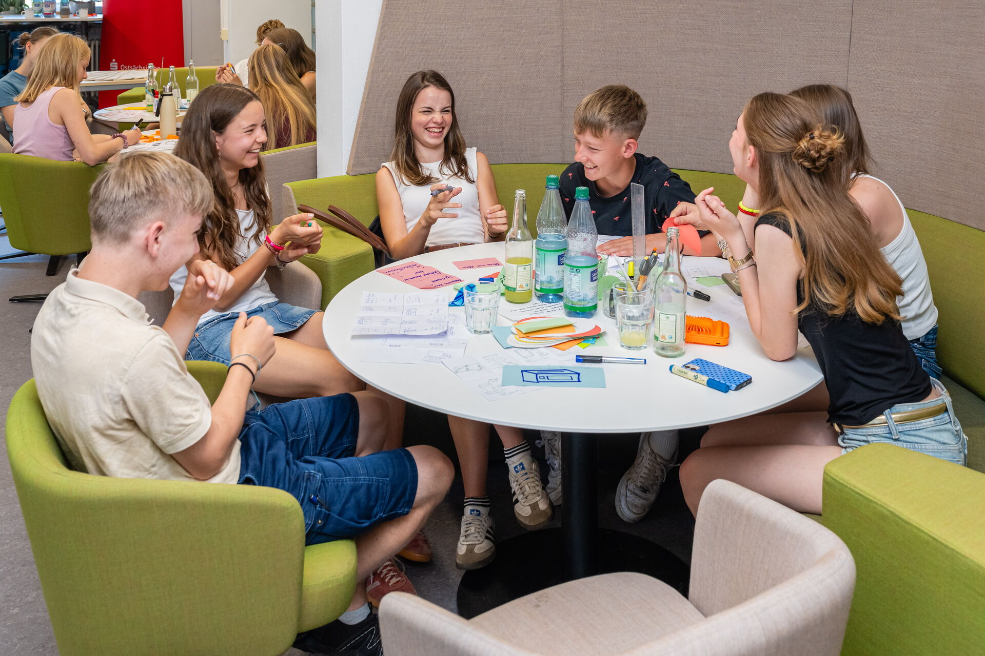 Schüler*innen lachen an einem runden Tisch