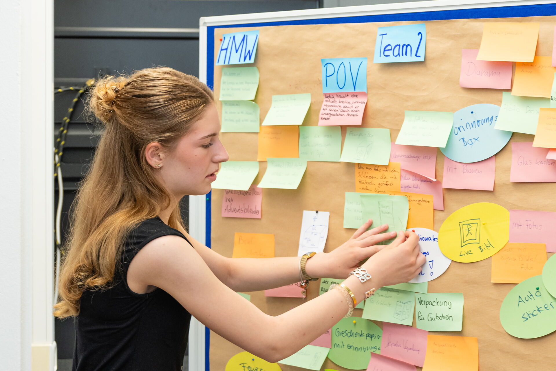 Eine Schüler*in mit Post-its an einer Pinnwand