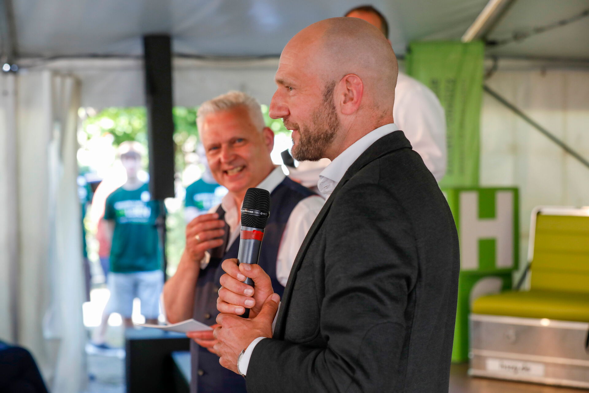 Landrat Dr. Stephan Meyer spricht auf der Bühne in ein Mikrofon, Thomas Krusekopfsteht hinter ihm.