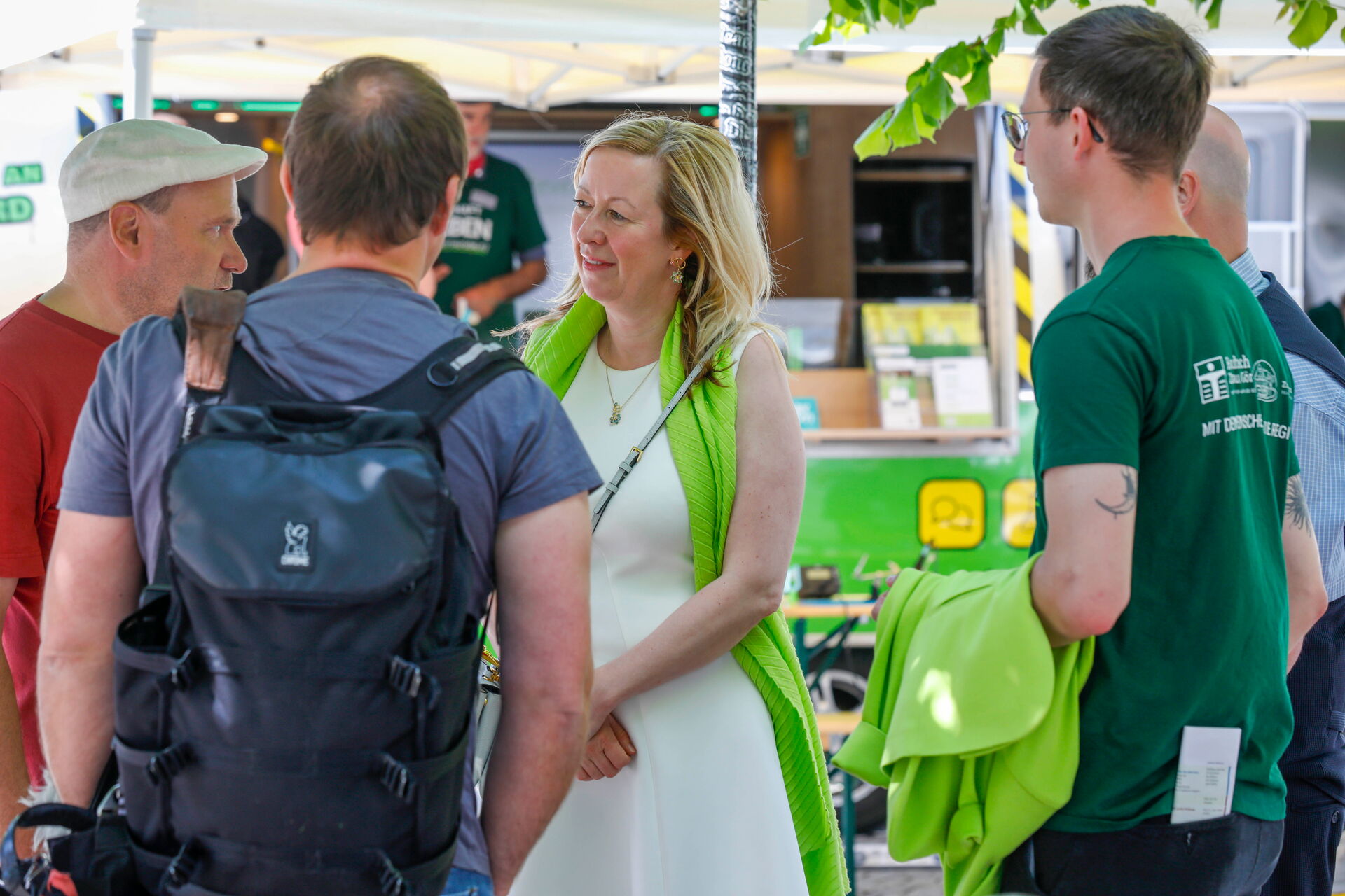 Mehrere Personen unterhalten sich vor einem mobilen Informationsstand im Freien.
