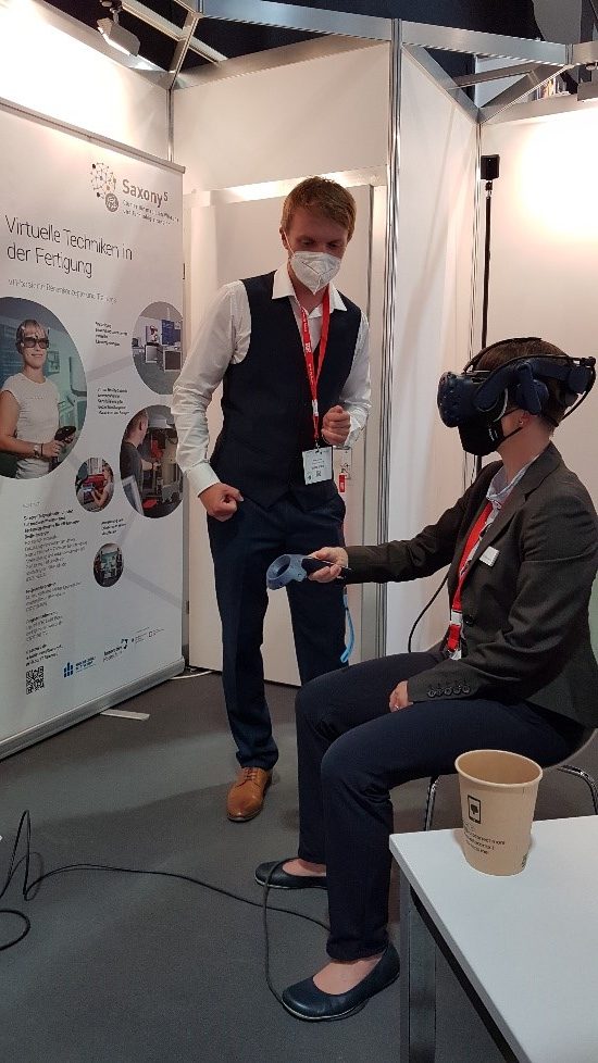 Eine Besucherin der aaa-Messe testet die Funktion der VR-Brille unter der Anleitung von Robert Eckardt.