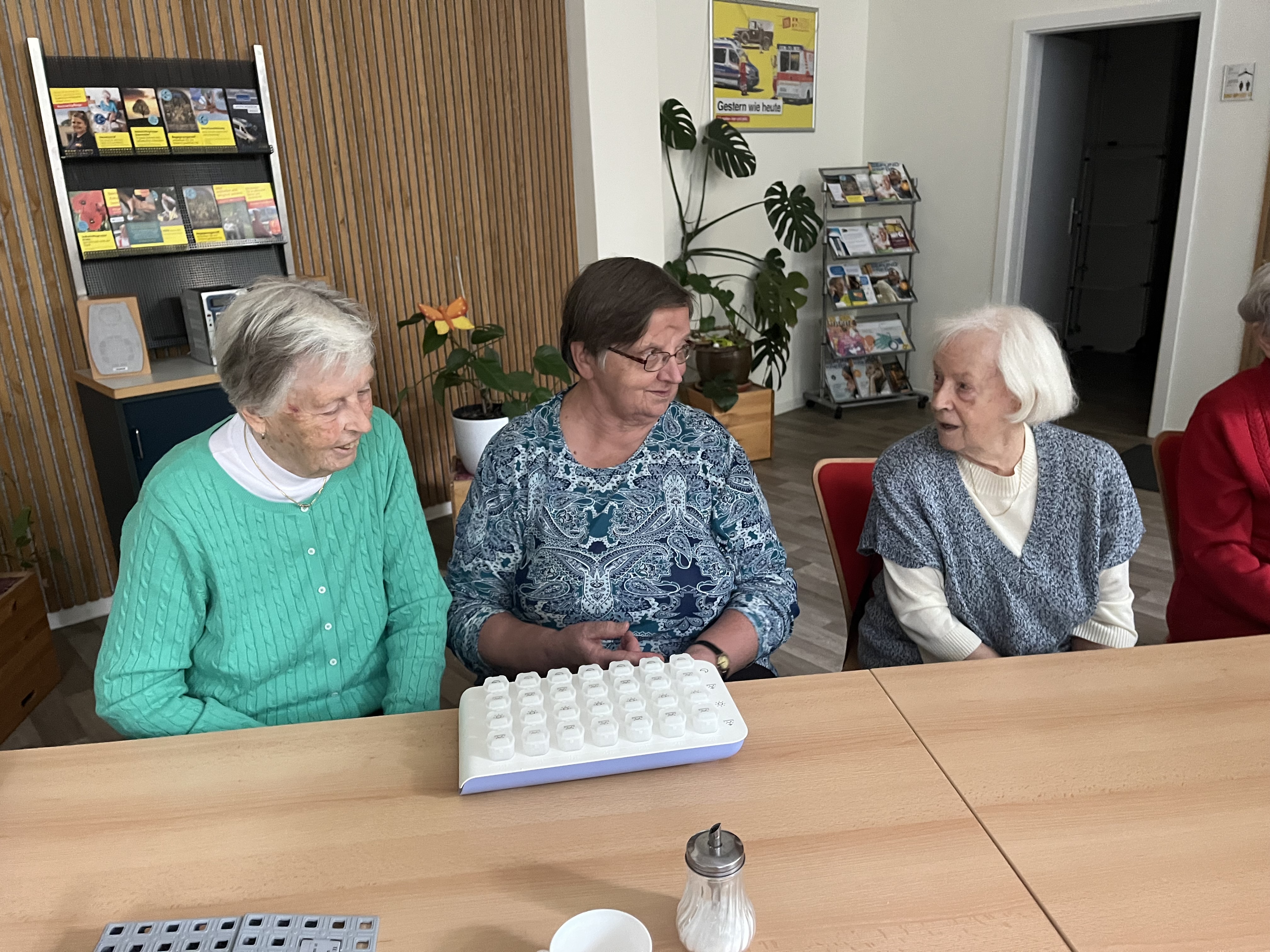 Drei Seniorinnen sitzen an einem Tisch. Vor Ihnen eine Smarte Medikamentenbox aus dem AAL-Labor