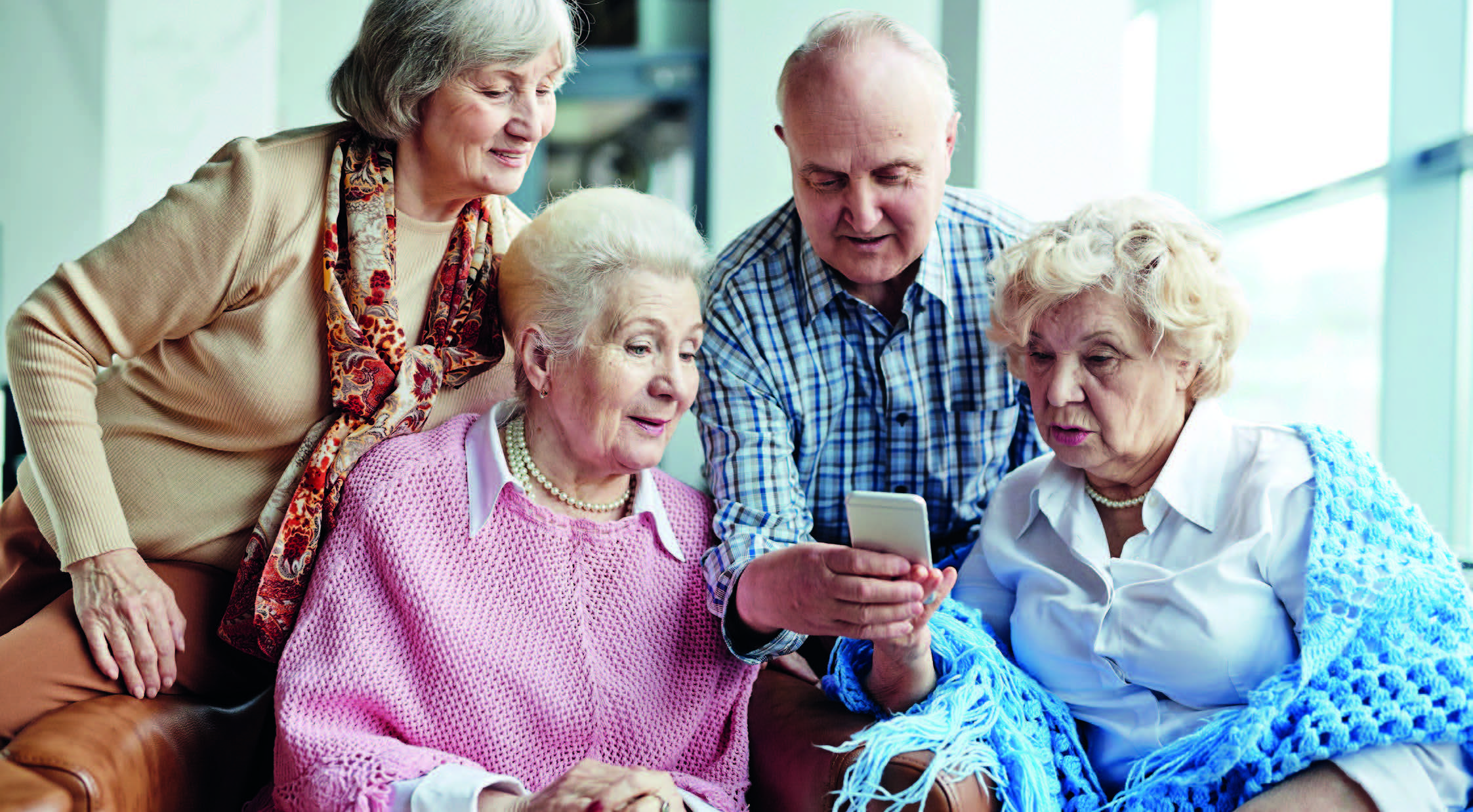 Senioren und Seniorinnen schauen zusammen auf ein Smartphone