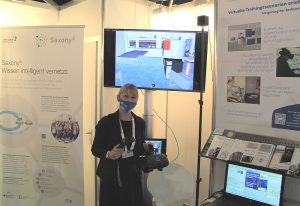 Wissenschaftlerin steht am Stand und präsentiert die VR Brille