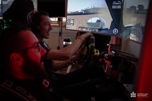 Zwei Männer sitzen vor einem Monitor und simulieren ein Motorsport-Event